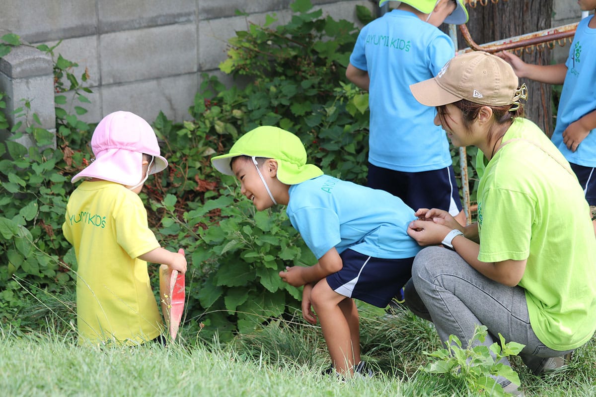 先生と草むらを観察する子どもたち