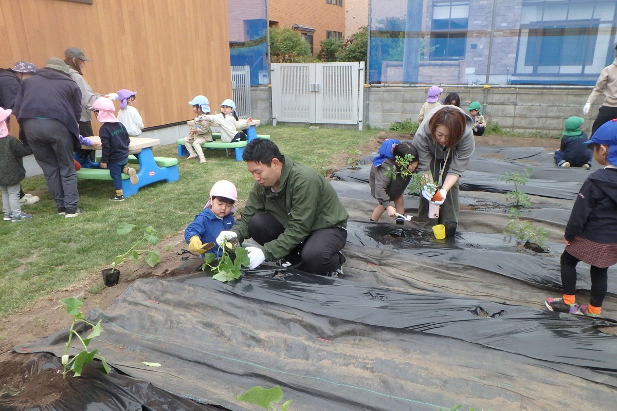 先生と泥遊びをする子どもたち