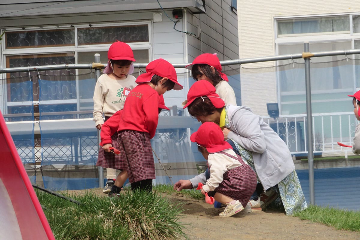 先生と砂遊びをする子どもたち
